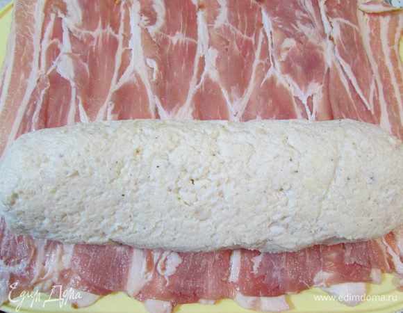 На рабочую поверхность внахлест выложите полоски бекона (12 шт.). Аккуратно переложите куриный рулет на бекон. 