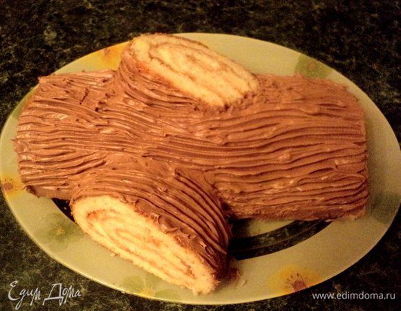 Формируем наше полено. Обрезаем края рулета с двух сторон, что бы был красивый разрез. Отрезаем  от рулета кусочек толщиной 7-8 см и разрезаем его наискосок. С помощью крема приклеиваем кусочки к рулету, это будут сучки полена. Смазываем рулет шоколадно-ореховым кремом и вилкой наносим рисунок коры.