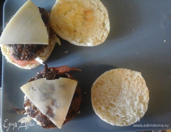 Разрезаем шарик. Нижнюю часть мажем соусом, кладем овощи, котлетку, сверху сыр и закрываем 2 половинкой.