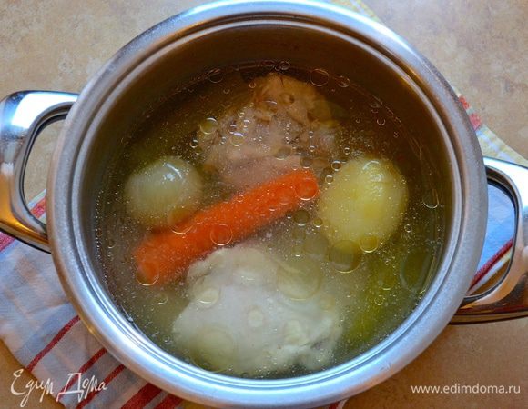 Первым делом приготовить бульон. Для этого в кастрюлю положить куриные бедрышки, очищенные овощи, залить достаточным количеством воды и поставить вариться на полтора часа. 