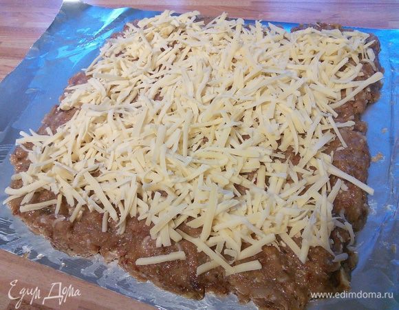 Фольгу смазываем оливковым маслом и выкладываем фарш прямоугольником. Маслом смазываем для того, чтобы фарш не прилип. Сыр трём на тёрке, выкладываем поверх фарша. Затем слой овощей. На сковородке вытапливаем бекон и выкладываем шкварочки на овощи. 