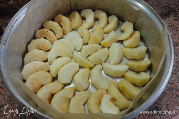 Яблоки очистить от кожуры и сердцевины и каждое разрезать на 8 частей. Форму полностью выстлать пекарской бумагой и смазать ее растительным маслом. Выложить половинки яблок.