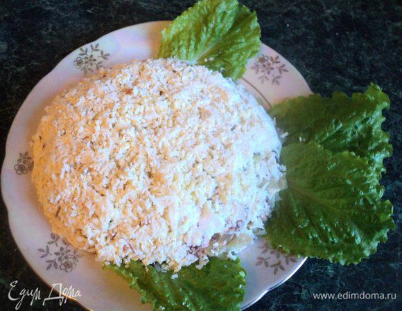 Из яйца вырезать один кружок, он будет глазом рыбки. Оставшиеся яйца  натереть на мелкой терке поверх рыбного слоя. Аккуратно ножом подравнять края рыбки. Покрыть сеточкой из майонеза ту часть рыбки, где будет чешуя.