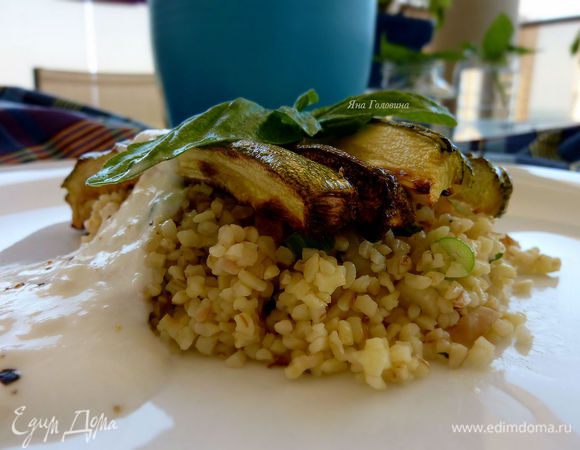 Зелень измельчить и перемешать с булгур. Посолить, сбрызнуть лимоном и оливковым маслом. Перемешать йогурт с лимонным соком по вкусу, выдавить чеснок через пресс и перемешать. На тарелку выложить булгур, сверху разложить кабачки и полить йогуртом.