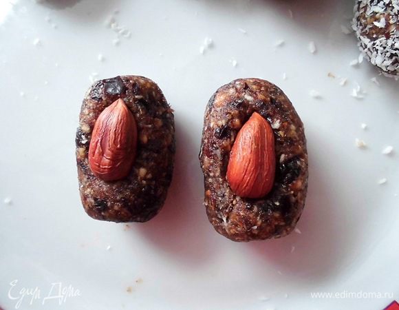 Все перемешать и добавить чуть больше половины кокосовой стружки. Снова перемешать. Скатать шарики, сделать из них колбаски. Вдавить в каждую из них по орешку и обвалять в кокосовой стружке. У меня получилось 27 штук.