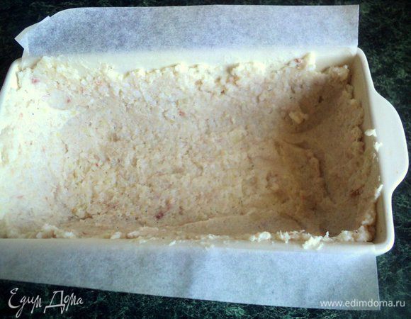 Форму размером 20х10 см застелить бумагой для выпечки, смазать растительным маслом.  Выложить половину рыбно- рисовой массы и равномерно распределить ее по дну и стенках формы. 