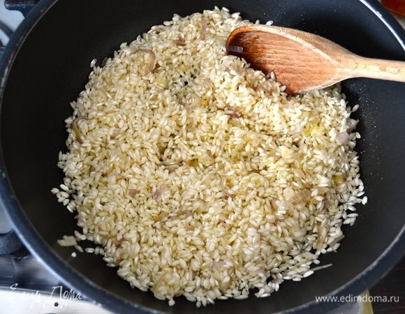 Всыпать рис (предварительно не промывать!) и обжарить все вместе пару минут, помешивая, чтобы рис перемешался с ароматами лука. Влить белое вино и позволить ему выпариться.  