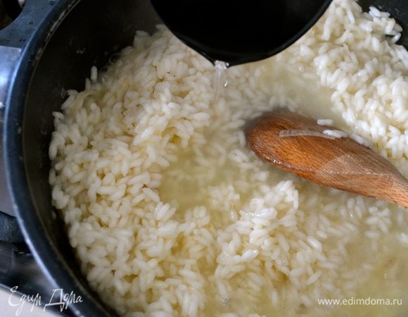 Влить пару половников горячего бульона. Не буду в данном рецепте подробно останавливаться на бульоне. Подробнее о нем можно прочитать в других моих рецептах ризотто. Например, здесь http://www.edimdoma.ru/retsepty/67227-rizotto-s-pryanymi-travami-dlya-yuli-shprot Готовить ризотто, подливая понемногу бульон, по мере того, как он будет впитываться рисом. В процессе посолить.