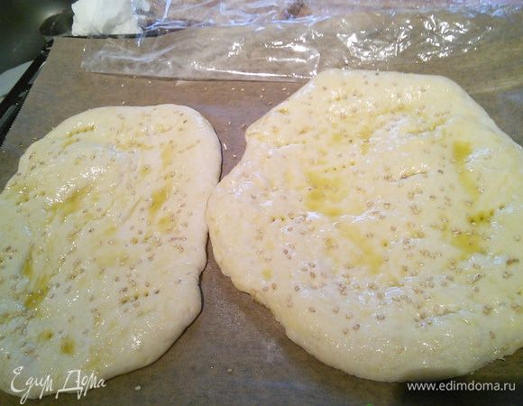 Выложите лаваш  на противень, накройте плёнкой и оставьте на 30 мин в тёплом месте. Сделайте вилкой дырочки, смажьте оливковым маслом, посыпьте сезамом и выпекайте в заранее разогретой духовке при 250°С в течении 15 мин. 