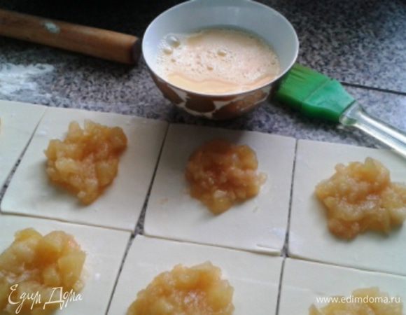 В центр каждого квадрата положить по одной столовой ложке начинки. Взболтать яйцо и смазать кисточкой края квадратов. 