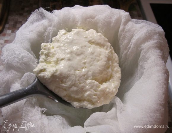 Готовим дуршлаг, шумовку, марлю в шесть сложений и емкость для сыворотки. Выстилаем дуршлаг марлей, ставим над миской и аккуратно, шумовкой, перекладываем сыр в марлю. Оставшуюся в кастрюле сыворотку процеживаем и переливаем в отдельную бутылку. Это очень ценный продукт, который нам еще пригодится. Накрываем сыр блюдцем подходящего диаметра, сверху ставим небольшой груз и убираем либо в холодильник, либо в другое прохладное место от +2 до +10 градусов (либо холодильник, либо утепленная лоджия) для остывания.