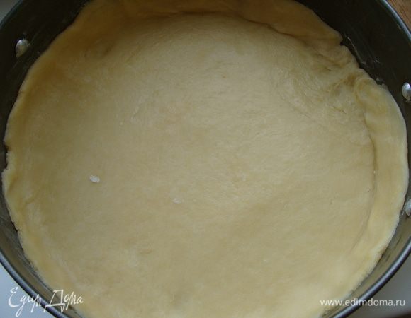 Тесто разделим на два кусочка. Один из которых немного побольше. Его раскатать, диаметр чуть больше формы для выпечки. Форму смазать сливочным маслом. Диаметр формы - 24 см. Уложить лепешку в форму, подмяв края.