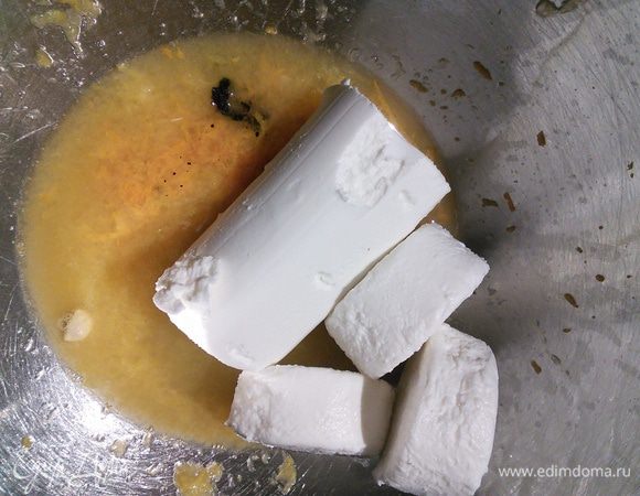 Замочите желатин в небольшом количестве холодной воды. У апельсина снимите цедру, из половины апельсина выдавите сок. Цедру второй половины апельсина оставьте для украшения (её срежьте ножом или спец. шкрябкой). Ваниль разрежьте вдоль и тупой стороной ножа выньте зёрнышки. Смешайте 2 ст.л. сока, цедру половины апельсина, ваниль, 2 ст. л. сахара с сыром в однородную массу. 2 ложки этой массы нагрейте в отдельной ёмкости и растворите в ней 3 пластины желатина, затем введите в остальную сырную массу. 