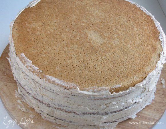 Положить один корж на другой, накрыть третьим бисквитным коржом, промазать бока торта.