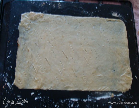 На стол кладем полотенце. Сверху теплый (не сильно горячий) противень вверх дном. Это очень удобно!

Присыпаем его мукой. Скалку тоже посыпаем мукой. Выкладываем шар и аккуратно раскатываем в  прямоугольную или круглую форму. Сверху необходимо положить шаблон и обрезать неровные края. Обрезки не убираем, они пригодятся для крошки, которой можно будет посыпать торт.
Печем на двух противнях до золотистого цвета 5-7 минут, пока один раскатываем, другой ставим в печь.