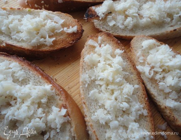 Сыр (у меня Асьяджио, мне нравится его нежный вкус и уникальная способность таять) натереть и посыпать ломтики багета.