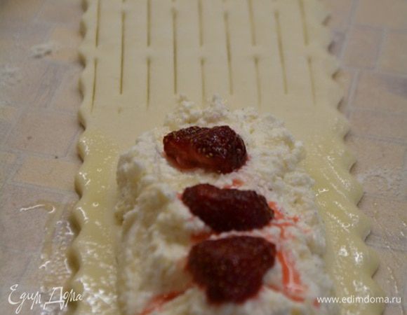 Тесто заранее разморозить и раскатать в одном направление не очень тонко!Разрезать пласт на прямоугольники шириной 5-6 см. На одну половину тесто выложить 1 ст.л творога, отступив от края 0,5-1 см, на творог клубнику (предварительно разморозить и дать стечь лишней жидкости). Края смазать смесью яйца и молока.