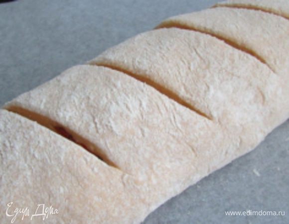 Переложить батон на противень. Ножом сделать насечки. Накрыть салфеткой и дать 20 минут на расстойку. Затем отправить в разогретую духовку (200 градусов), выпекать 35-40 минут. Готовность проверить деревянной шпажкой.