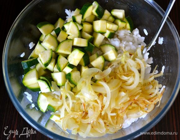 В миску с остывшим рисом положить нарезанные цукини и лук.