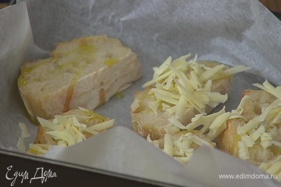 Небольшую форму для выпечки выстелить пищевой бумагой, выложить хлеб, сбрызнуть оливковым маслом, посыпать сыром и отправить под гриль на 2–3 минуты.