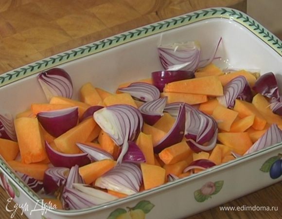 Лук почистить, нарезать крупными дольками и отправить к тыкве.