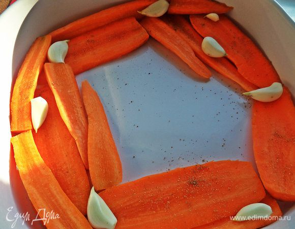 Керамическую форму смазать маслом и выложить по краям ломти моркови, сверху чеснок, кориандр, соль, перец и сбрызнуть сверху маслом.