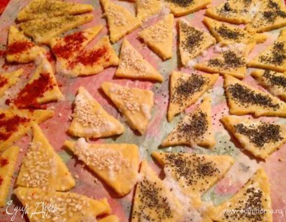 Затем разделить шар пополам и каждую часть раскатать на пергаментном листе в квадрат 20х20 см, разрезать на 16 квадратов и каждый перерезать по диагонали, чтобы получились треугольники.

Смазать треугольники взбитым белком и присыпать маком, кунжутом, орегано, сладкой паприкой, розмарином, а можно и просто солью на ваше усмотрение.
Мне больше всего нравятся треугольники с маком и кунжутом.