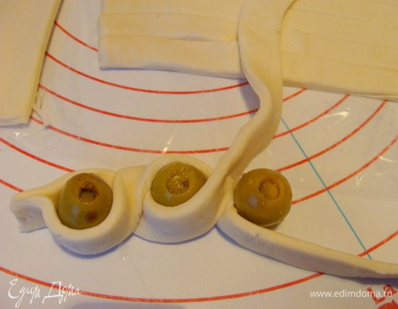 Взять две полоски, слепить концы и, вставляя оливки, заплести косичку (жгут).