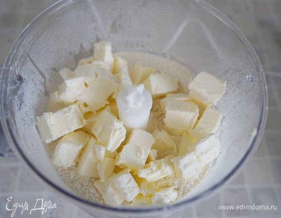 Приготовим рубленое тесто: в миске блендера смешать муку, соль, сахар. Очень холодное масло порезать на кусочки и добавить в муку. За несколько пульсаций миксера измельчить в крупную крошку.
