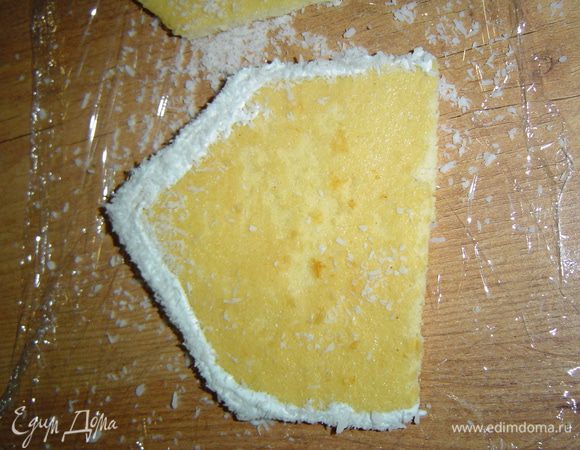 Подготовленные украшения в виде домиков смазываем края сливками и посыпаем кокосовой стружкой.