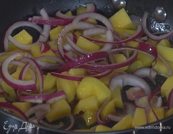 Лук почистить, нарезать тонкими полукольцами и добавить в сковороду с картофелем.