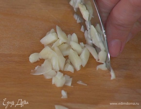Чеснок почистить, раздавить, мелко порезать и добавить к луку с картофелем.