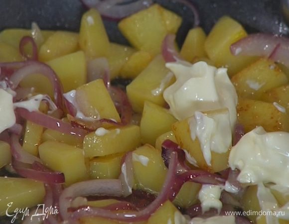 На обжаренный картофель с луком выложить сметану (перемешивать не обязательно!).