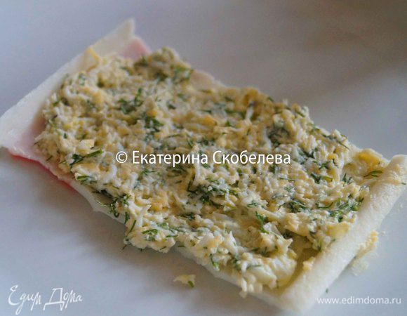 Поверх крабовых палочек выложить небольшое количество начинки.