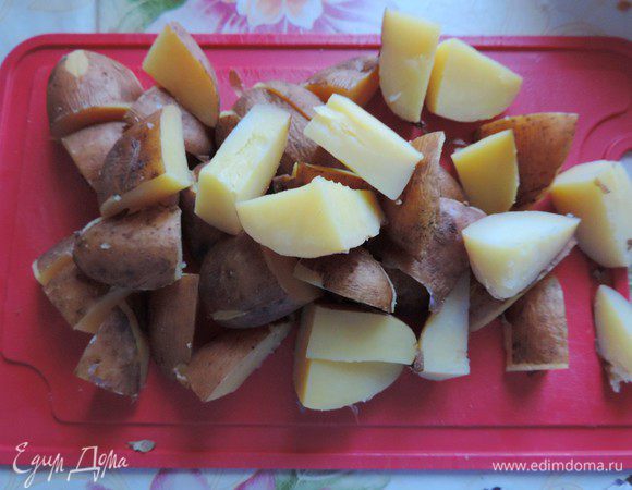 Картофель тщательно моем и отвариваем в кожуре до готовности. Я рекомендую сделать это заранее, тогда времени на приготовление блюда потребуется совсем немного.
Отварной остывший картофель нарезаем на крупные кусочки. Я каждую картофелину разрезала на 8 частей.