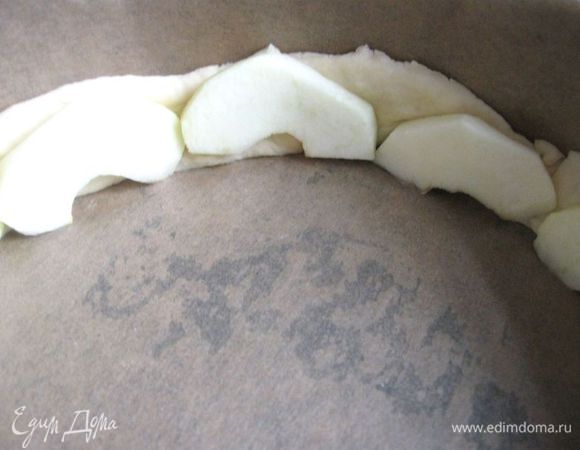 В форму, застеленную пекарской бумагой, начать укладывать сначала  1 полоску, на нее – дольки яблок, затем другую – опять яблочные дольки. 