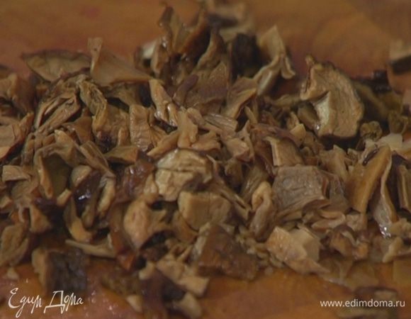 Размоченные грибы мелко порезать, выложить в сковороду к луку, перемешать, немного посолить и поперчить, добавить орегано.
