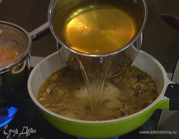 Рис всыпать к грибам с луком, посолить и перемешать, затем влить вино, воду, в которой замачивались грибы, и 400–500 мл горячего овощного бульона. Готовить, не закрывая крышкой, подливая по мере выкипания жидкости оставшийся бульон.