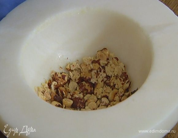 Обжаренные орехи измельчить в ступке так, чтобы остались крупные кусочки.