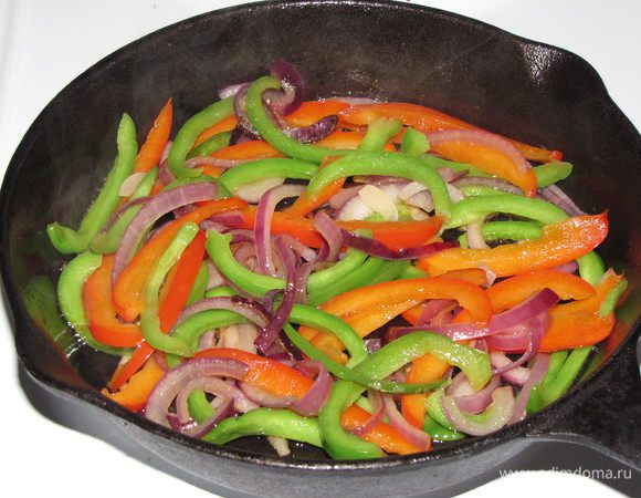 Разогреть в сковороде оливковое масло, выложить перец и лук и обжаривать 10 минут, перец должен стать мягким, а лук прозрачным.