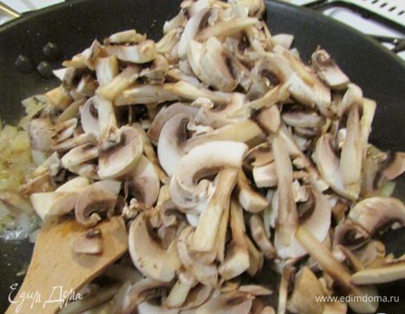 В сковороде нагрейте растительное масло, положите лук, обжарьте на среднем огне до золотистого цвета, добавьте грибы, увеличьте огонь и обжаривайте 5 минут. Всыпьте муку и обжаривайте ещё 2 минуты. 