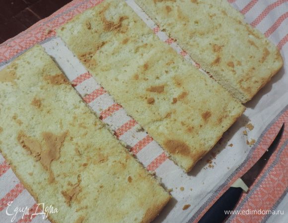 С остывшего бисквита аккуратно снимаем верхнюю запеченную корочку. Она нам пригодиться для посыпки. Подготовленный таким образом бисквит разрезаем поперек на три одинаковых пласта.