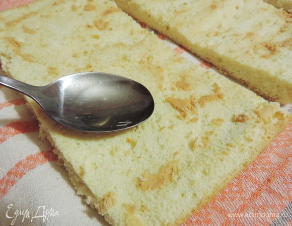 Заранее приготовим пропитку. В теплой воде растворяем сахар. Даем остыть до комнатной температуры и смешиваем с коньяком. Полученной пропиткой щедро пропитываем бисквитные пласты.