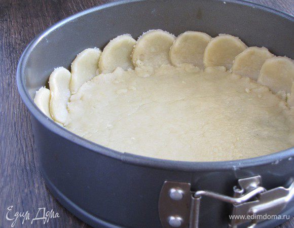 Вторую половину теста раскатать в круг и выложить на дно формы. На стыках с кружками прижать тесто руками.