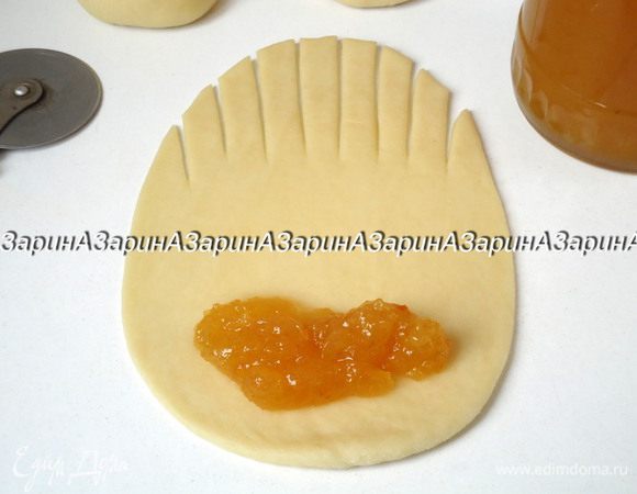 Из каждого шарика раскатать продолговатую лепешку. С одного края лепешки сделать, продольные надрезы на 1/3 её длины. На другой край лепешки положить по 1 ложке повидла.