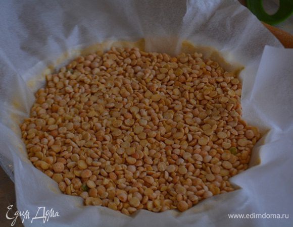 Духовку разогреть до 200 градусов. Тесто раскатать в пласт на присыпанном мукой столе. Аккуратно перенести в форму, сделать бортики, наколоть поверхность вилкой. На тесто уложить бумагу для выпечки и насыпать фасоль или горох.Запечь в духовке 10 минут.