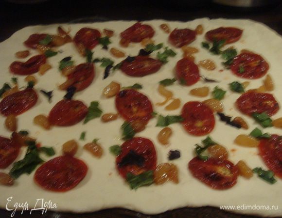 Выложить тесто на посыпанную мукой рабочую поверхность. Раскатать в прямоугольник. На тесто выложить помидоры, печеный чеснок и базилик.