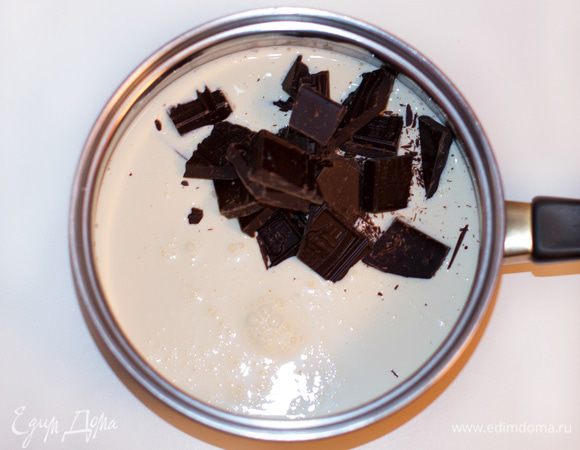 Пока бисквит остывает, приготовить ганаш. В жаропрочную емкость налить сливки, добавить поломанный на кусочки шоколад. Прогреть, постоянно помешивая, до полного растворения шоколада, но не кипятить. Как только шоколад растворился в сливках, снять с огня. Накрыть емкость крышкой или пленкой и дать остыть.