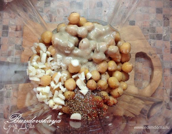 Переложить нут в чашу блендера, добавить все остальные ингредиенты, кроме оливкового масла. Пюрировать до однородного состояния. Если пюре слишком  густое, добавить пару столовых ложек холодной воды. Не выключая блендера, влить тонкой струйкой оливковое масло. В зависимости от количества масла хумус получится более или менее кремовой текстуры.