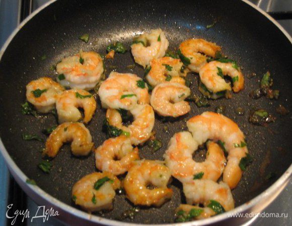 В сотейнике разогреть оливковое масло. Обжарить чеснок, чеснок убрать. Обжарить креветки на сильном огне, посолить, добавить петрушку.
